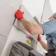 Worker adding tile to bathroom wall