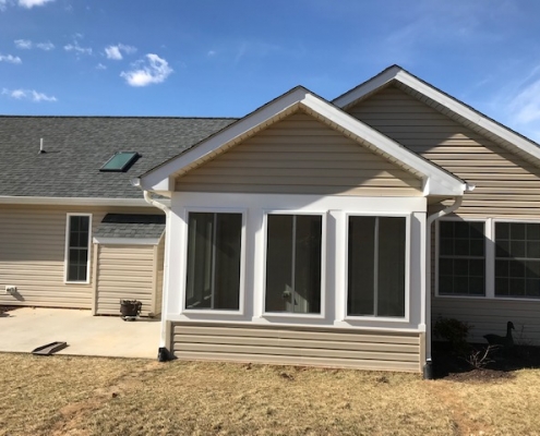 direct image of a tan sunroom with vinyl siding