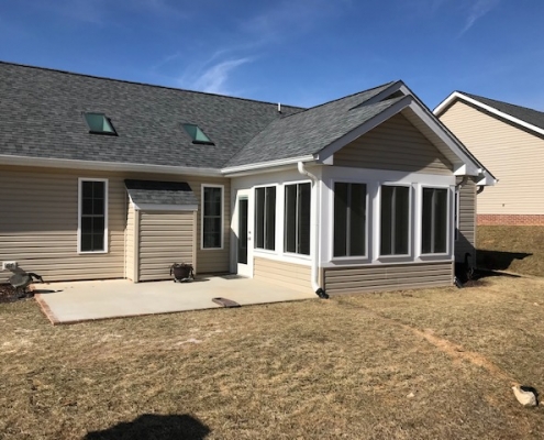 A tan sunroom with vinyl siding