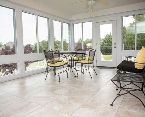 Interior of sunroom with tile flooring and furniture.