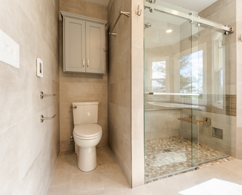 Custom over-the-toilet cabinetry and walk-in shower in a spa-worthy bathroom renovation.