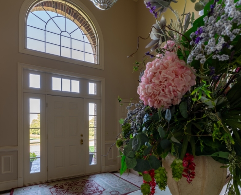 A foyer near a home's front entrance shows the front door, windows and a flower arrangement.