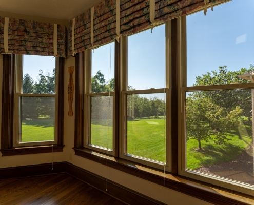 An interior sunroom with large windows looking into the backyard.